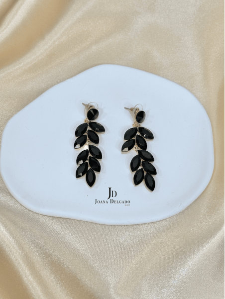 Pendiente metálico en color dorado con piedras negras.