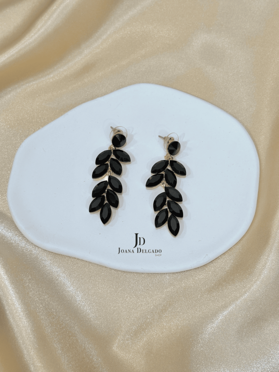 Pendiente metálico en color dorado con piedras negras.