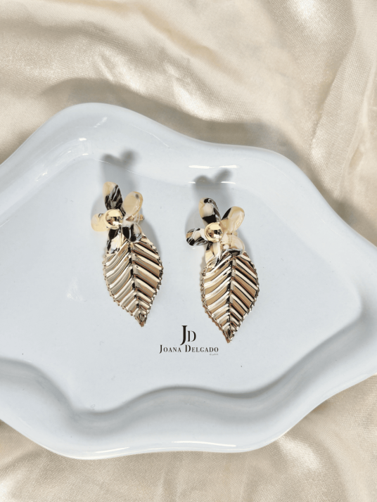 Pendientes con flor efecto nacarado y hoja colgante dorada.