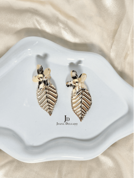 Pendientes con flor efecto nacarado y hoja colgante dorada.
