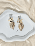 Pendientes con flor efecto nacarado y hoja colgante dorada.