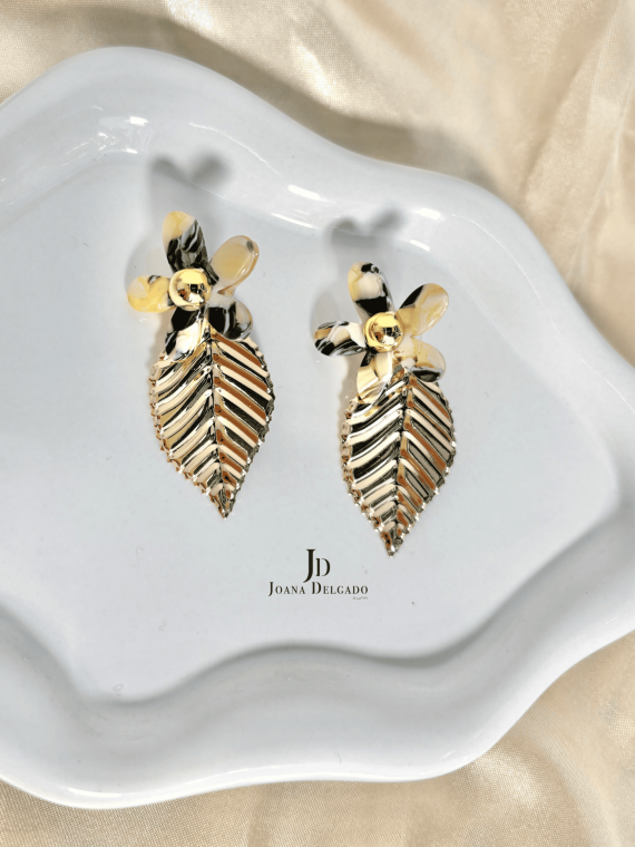 Pendientes con flor efecto nacarado y hoja colgante dorada.