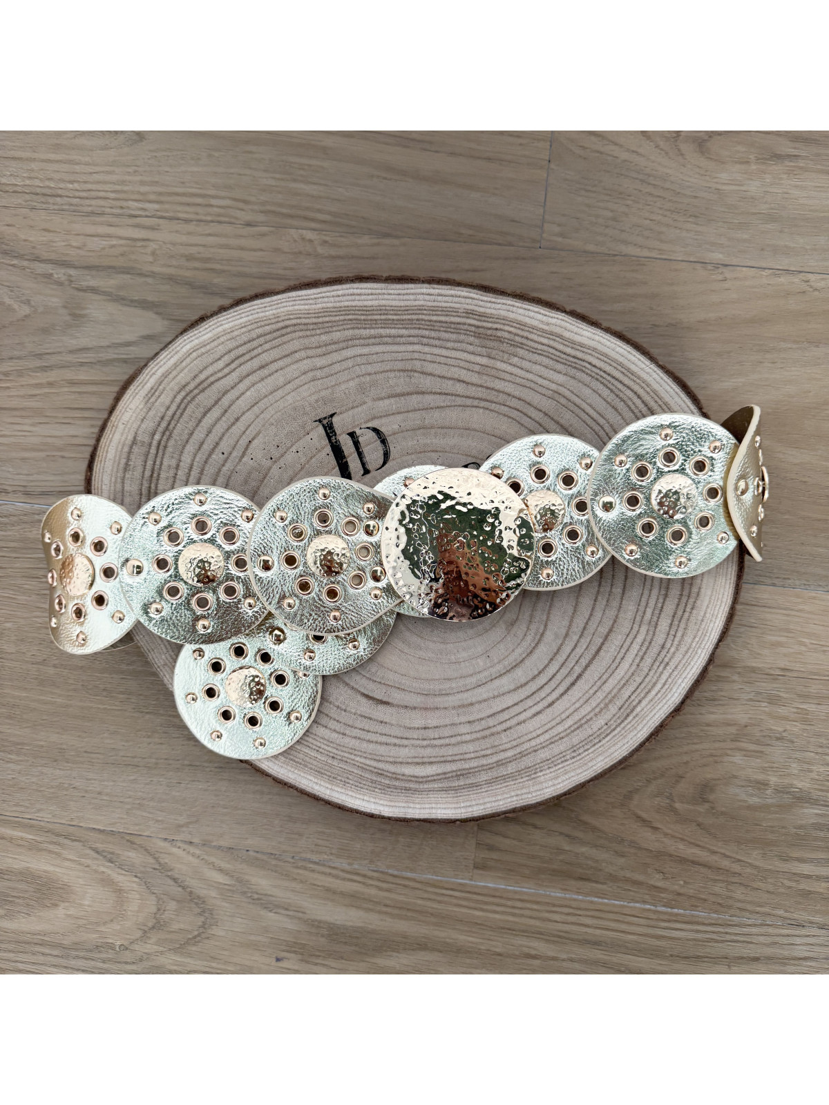 Cinturón de polipiel dorado formado por círculos.