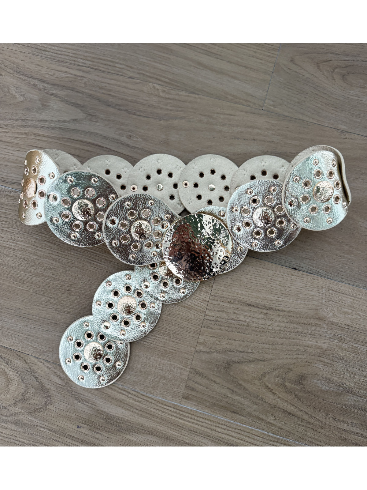 Cinturón de polipiel dorado formado por círculos.