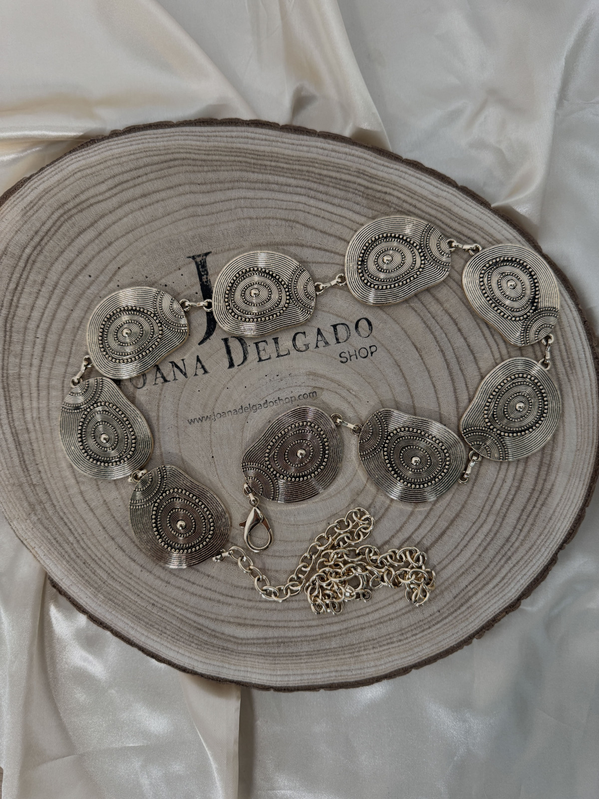 Cinturón metálico dorado con cadena y medallones.