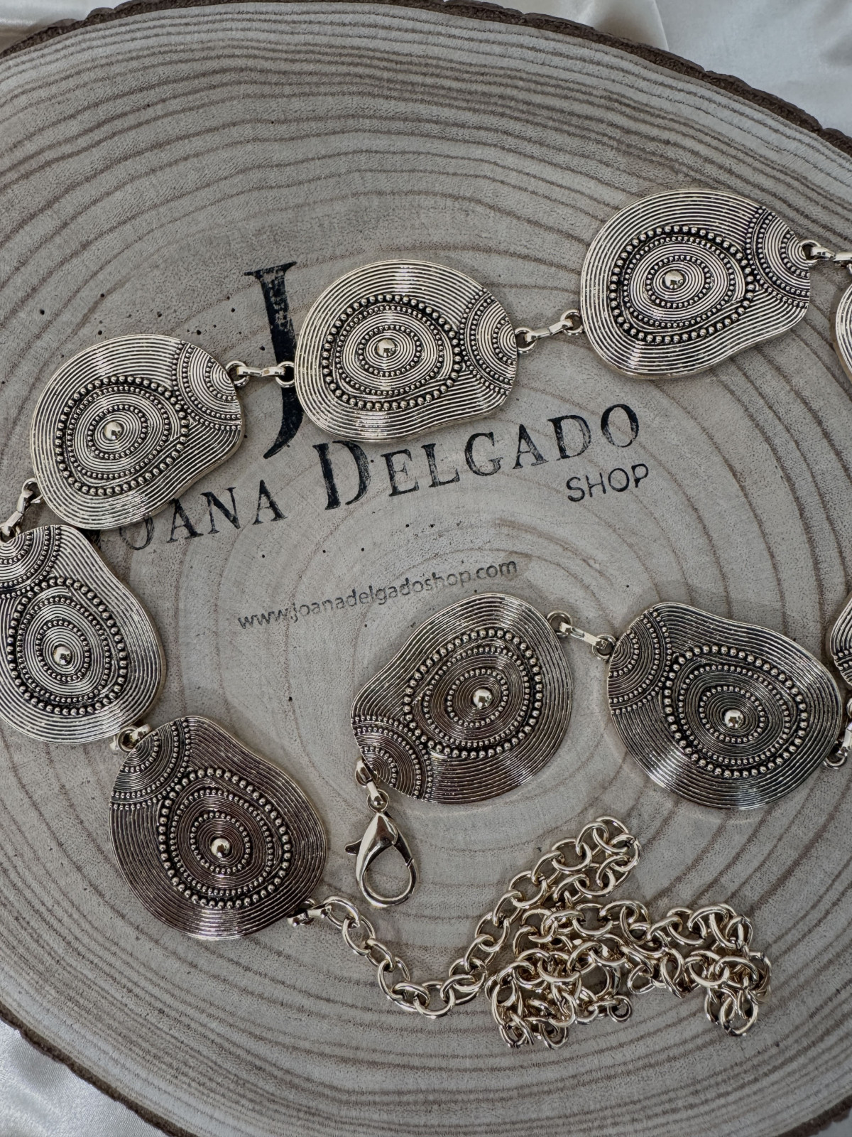 Cinturón metálico dorado con cadena y medallones.