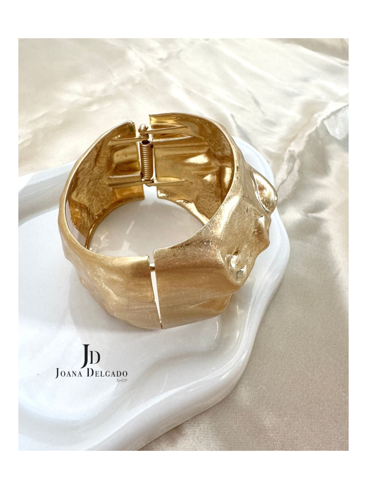 Brazalete metálico dorado con relieve.