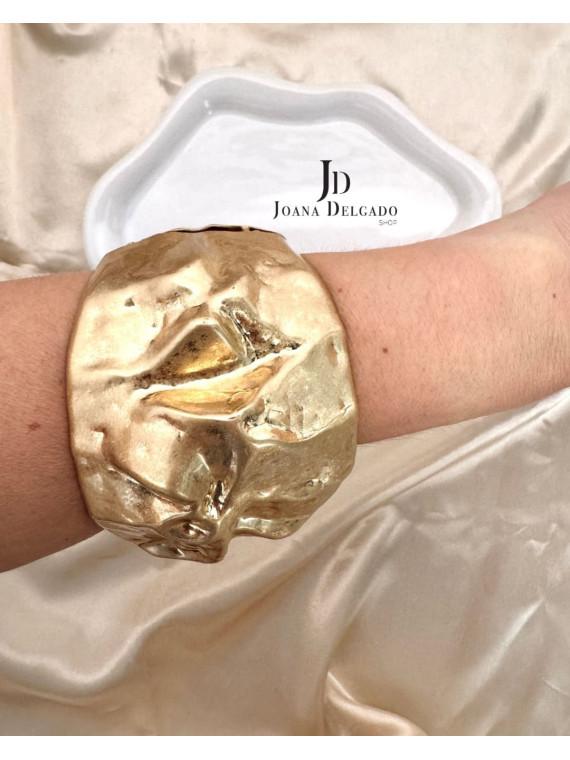 Brazalete metálico dorado con relieve.