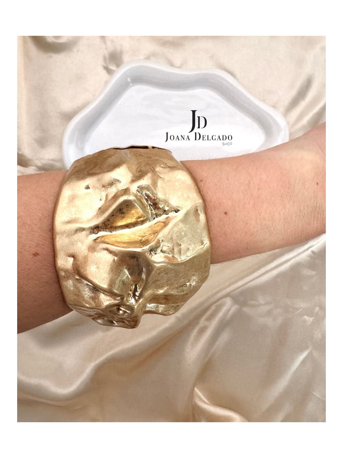 Brazalete metálico dorado con relieve.