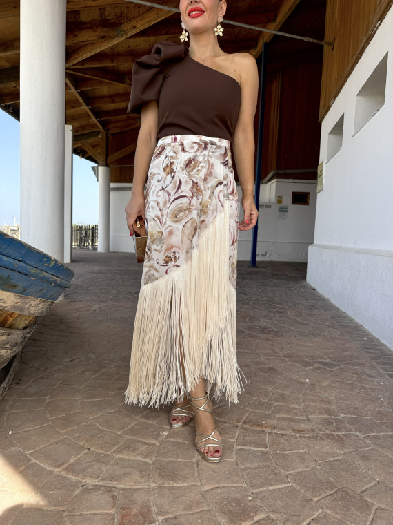 Falda de fiesta en tejido satinado estampado y adornada con flecos.