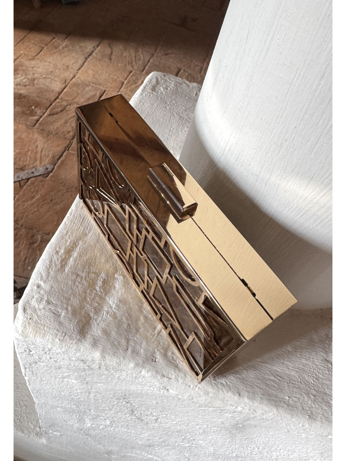 Bolso nacarado con montura en color dorado, en tonos color marrón.