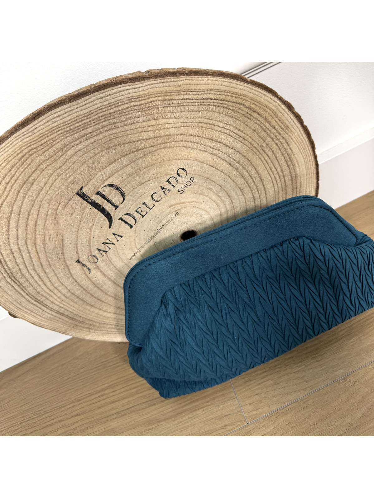 Bolso de mano azul petróleo con textura plisada.