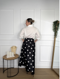 Falda midi en color negro con estampado de lunares blancos.