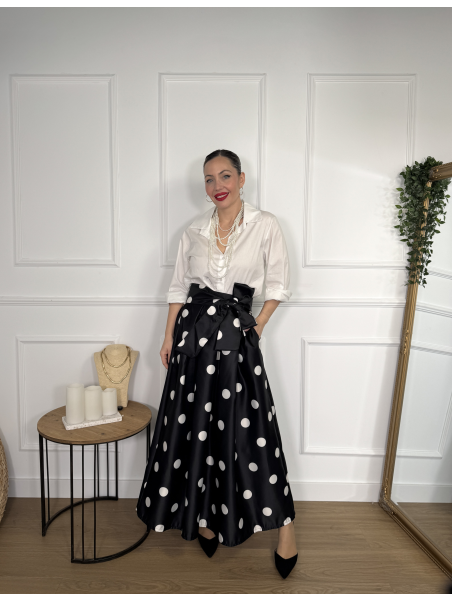 Falda midi en color negro con estampado de lunares blancos.