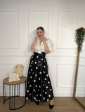 Falda midi en color negro con estampado de lunares blancos.