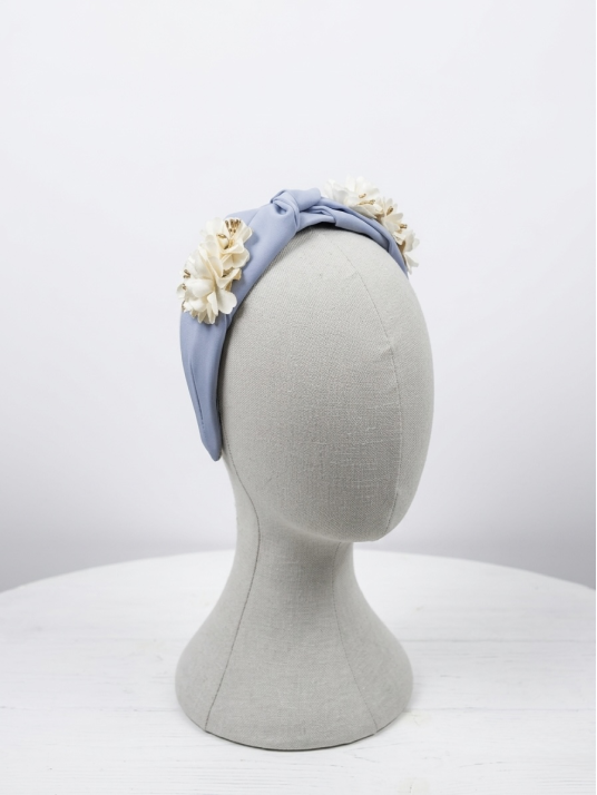 Diadema en tono celeste con delicado nudo central, adornada con flores