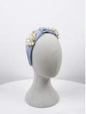 Diadema en tono celeste con delicado nudo central, adornada con flores