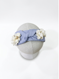 Diadema en tono celeste con delicado nudo central, adornada con flores