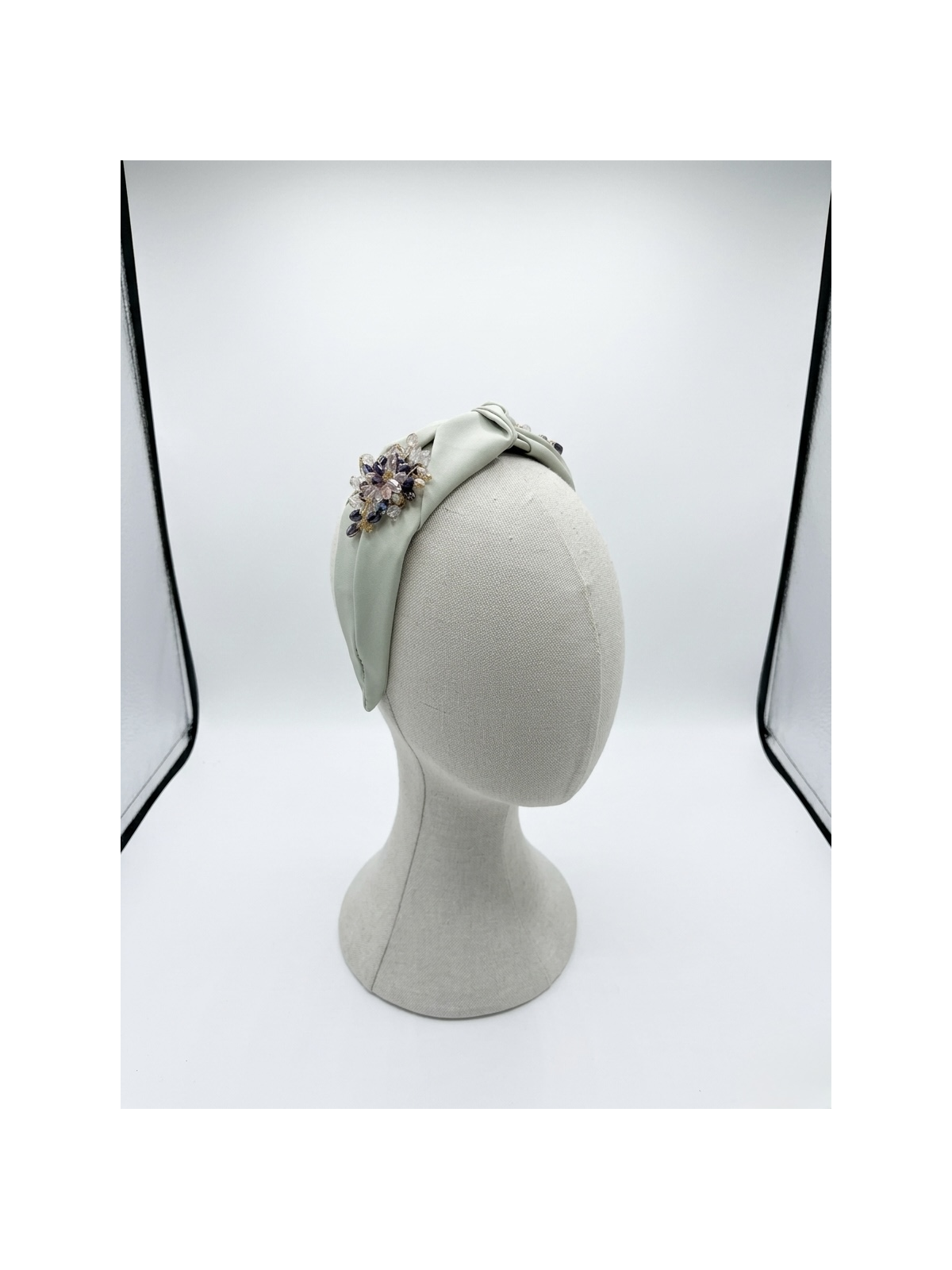 Diadema en tono verde suave con elegante nudo central, adornada con un