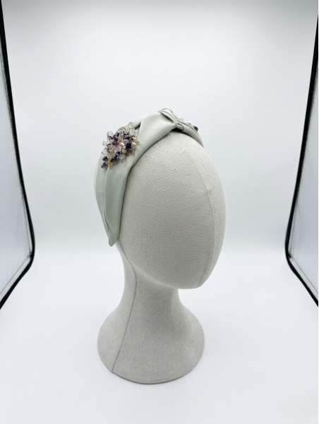 Diadema en tono verde suave con elegante nudo central, adornada con un