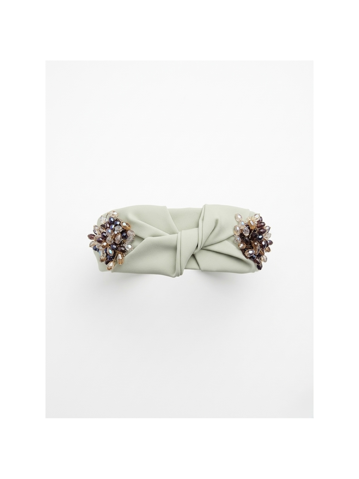 Diadema en tono verde suave con elegante nudo central, adornada con un