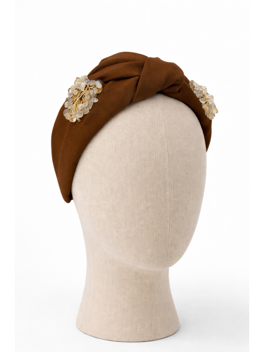 Diadema ancha en tono marrón con diseño anudado.